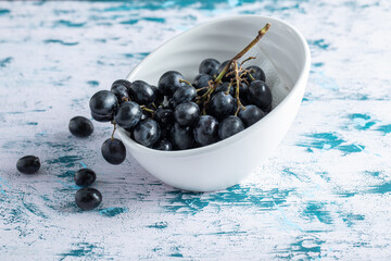 Dark fresh grape in bowl on a colorful background