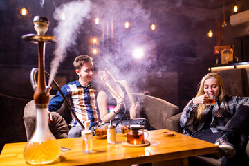 Friends party in hookah lounge smoking shisha night time