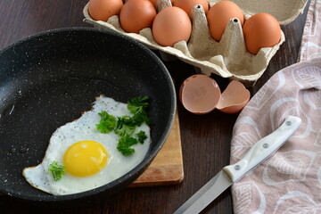 eggs in a frying pan on the cutting board with knife and egg tray