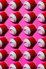 Pasttern, a lot of red paper cups for coffee or tea to go on a pink background. Disposable tableware on a colored background with copy space.