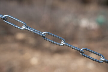 Connected steel chain outside in nature with brown background