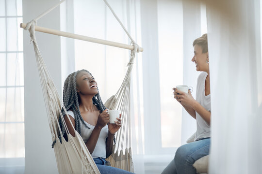Two girls having coffee in a light room and talking