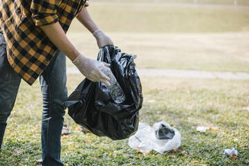 Male volunteers carry water bottles or plastic bags that have fallen in the park put them in trash cans, Environmental protection or volunteering for charity, Waste disposal through recycling.