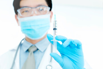 Male doctor, holding syringe with needle up, getting ready to do injections and cure patients