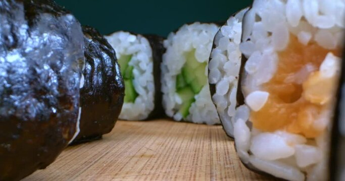 extremely close-up detailed plan of nori maki on a wooden board with various fillings.
