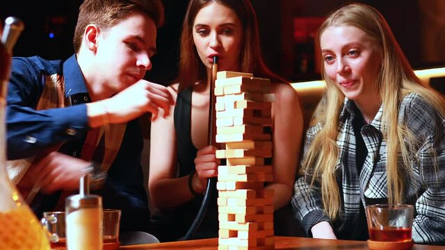 Young people have fun playing board games at a table in cafe