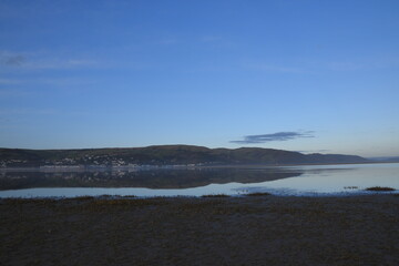 a view of the welsh mountains from ynyslas beach reflected in the estuary