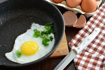 eggs in a frying pan on the cutting board with knife and egg tray