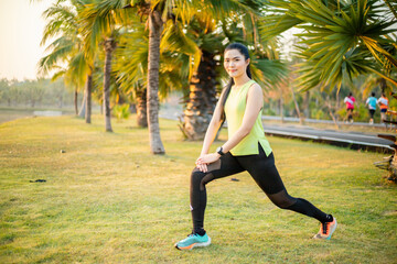 A young woman runner stretching her legs before running in the park