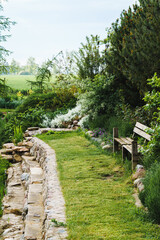 part of the garden along the edge of the pond, a wooden bench and the embankment of a pond built with stones