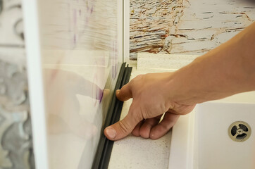 Installation, assembly, repair of kitchen furniture. Close-up of a worker's hand.