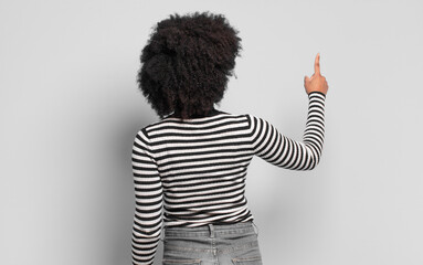  standing and pointing to object on copy space, rear view