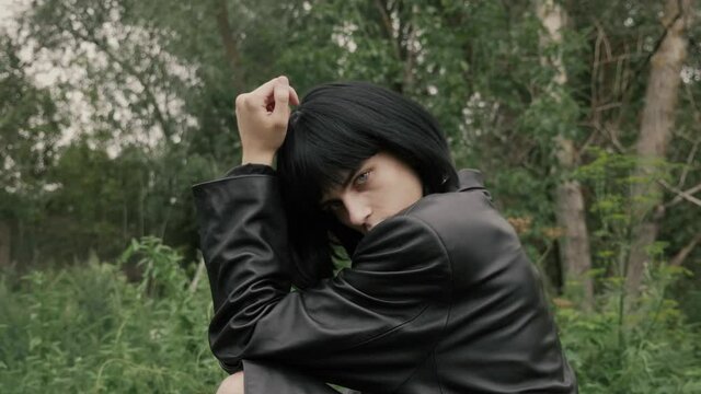 Gay twink in leather posing sensually and stroking face and lips with his thin fingers