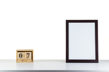 Wooden calendar 07 april with frame for photo on white table and background