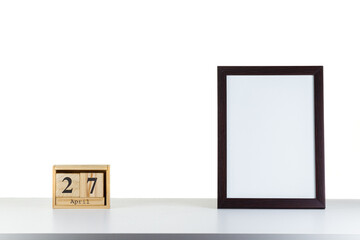 Wooden calendar 27 april with frame for photo on white table and background