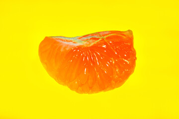 peeled slice of tangerine. textured fruit pulp. yellow background. isolate