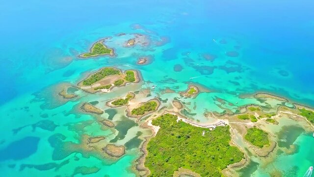 Aerial shot from bottom to top of the natural green islands of Monilia in Greece, with many rowing boats sailing on the sea