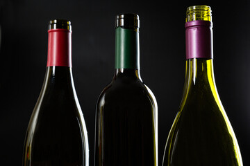 several open Bottles without wine labels stand against a dark glossy background.