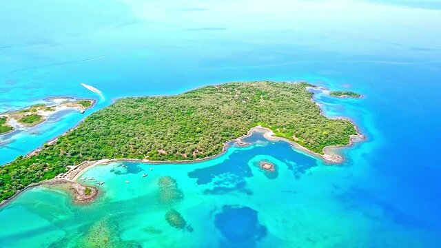 An aerial view of green islands of Monilia in Greece, with a yacht sailing between two islands