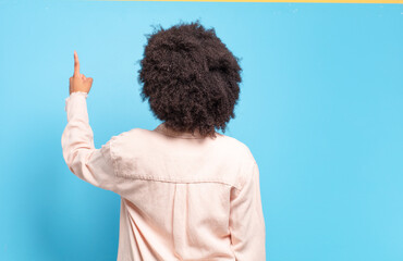  standing and pointing to object on copy space, rear view