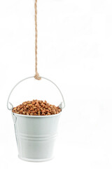 A full bucket of buckwheat grains hanging from a rope.