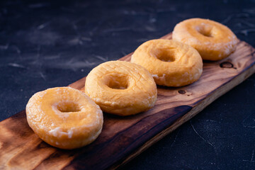glazed donuts on wooden base with dark background
