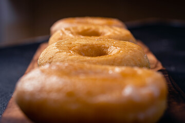 glazed donuts on wooden base with dark background