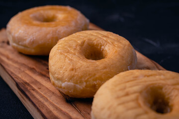 glazed donuts on wooden base with dark background