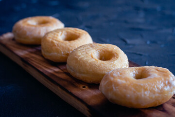 glazed donuts on wooden base with dark background