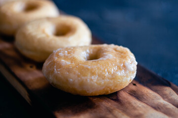 glazed donuts on wooden base with dark background