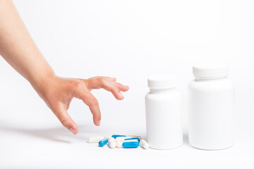 Child hand piccking pills on a white. Little hand takes drugs from container.