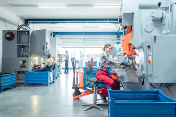 Woman worker in factory producing parts on punching machine