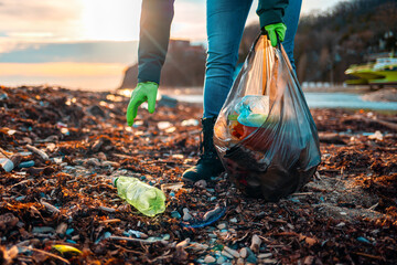 A volunteer collects garbage on a muddy beach. Close-up. The concept of Earth Day and Environmental...