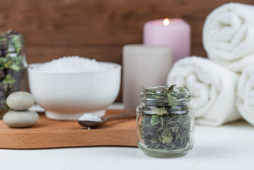 Fototapeta na wymiar Herbal therapy, traditional medicine and homeopathy concept. Towel with salt, herbs and aroma candles. Set for spa, massage and aromatherapy