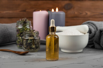 Fototapeta na wymiar Herbal therapy, traditional medicine and homeopathy concept. Towel with salt, herbs, candles and bottle natural organic oil essence serum. Set for spa, massage and aromatherapy