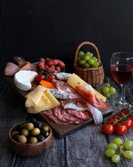 Antipasti, a traditional Italian appetizer and red wine on a dark wooden table. Sliced meat. - 416102613
