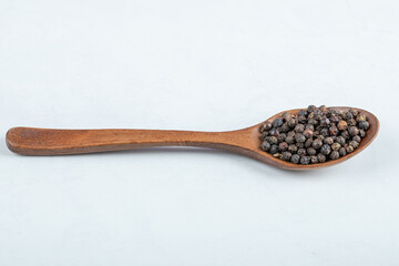 A wooden spoon full of dried pepper on a white background