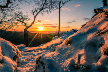 Beautiful winter landscape in the sunset. On a mountain with a forest and a beautiful view in the snow. Cold winter.