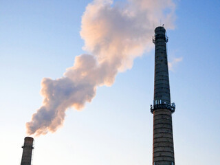 plant tubes with gray smoke on blue sky, chemical plant towers of nuclear power plant against the...