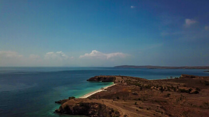 Obraz premium A panoramic view on an idyllic Pink Beach on Lombok, Indonesia. Sea is calm, shining with many shades of blue. Beauty in the nature. Unspoiled, hidden gem. Perfect place for peaceful, relaxed holidays