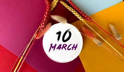 March 10 on a white round object.Near the sprigs of wheat on a colorful bright background.Calendar for March .