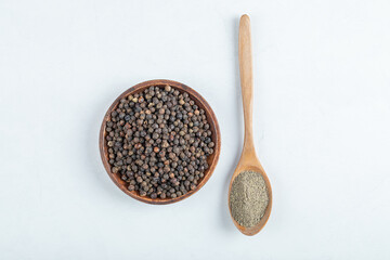 A wooden plate full of dried pepper on a white background