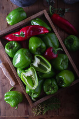Food preparation with fresh green bell pepper. Fresh green and red peppers in wooden box on the table. Top view.