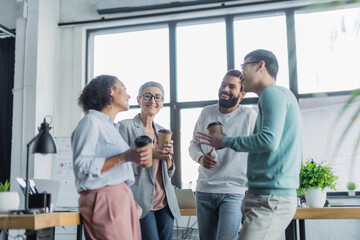 Smiling multiethnic business people with paper cups talking in office