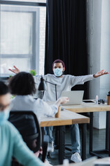 Obraz premium African american businessman in medical mask looking at colleagues