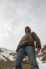 Stock photo of a man wearing camouflage clothing, and trekking in the high mountain of Moncayo in Aragon, Spain, surrounded by huge rocky and snowy hillside.