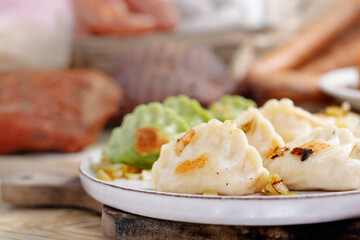 Close-up of dumplings, pierogi with chopped fried onion, on a white plate.