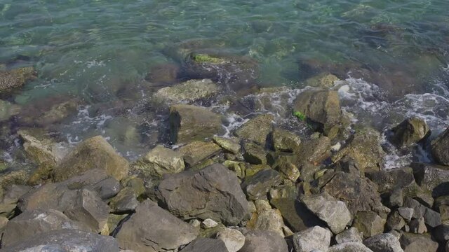 Sea waves break down on shore of bay rocks during sea surf. Top view.