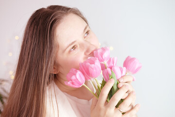 Obraz na płótnie Canvas young woman, girl with long blond hair holds bouquet of pink tulips in her hands, light toned photo, concept spring, mother's day, valentine's, birthday, holiday