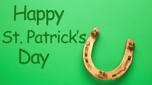 St. Patrick's day concept - horseshoe with inscription Happy St. Patrick's day on green background. Stop motion